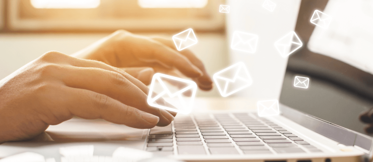 Person typing on laptop with many small envelope holograms 